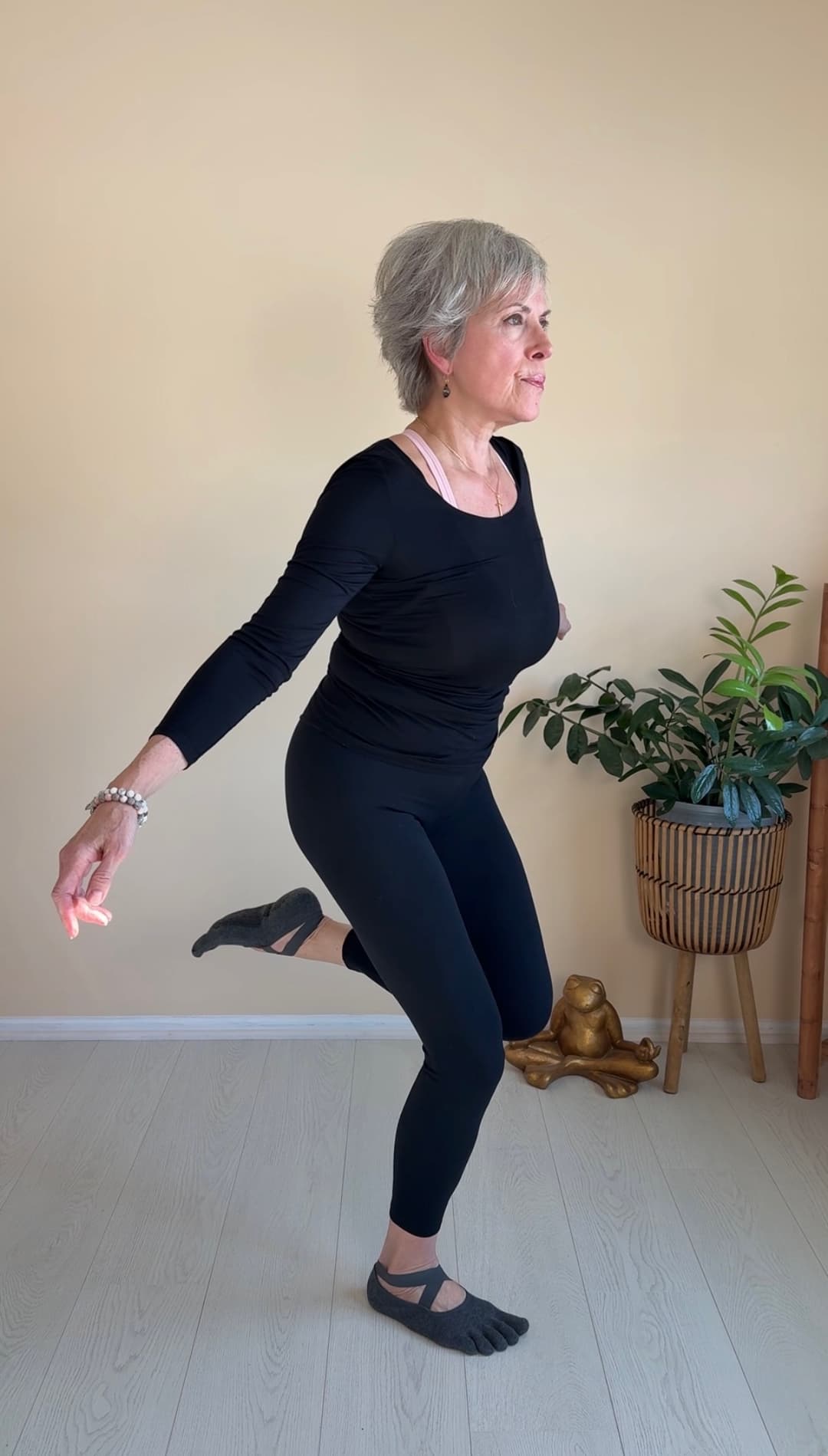 Christine Cernera performing a single leg balance exercise with arms extended, demonstrating excellent form